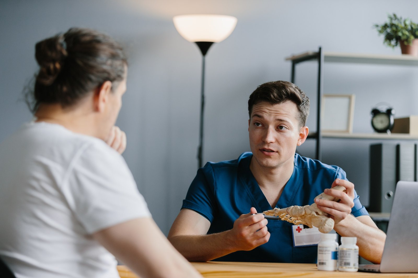 Doctor demonstrating a foot skeleton model to a patient in his office.